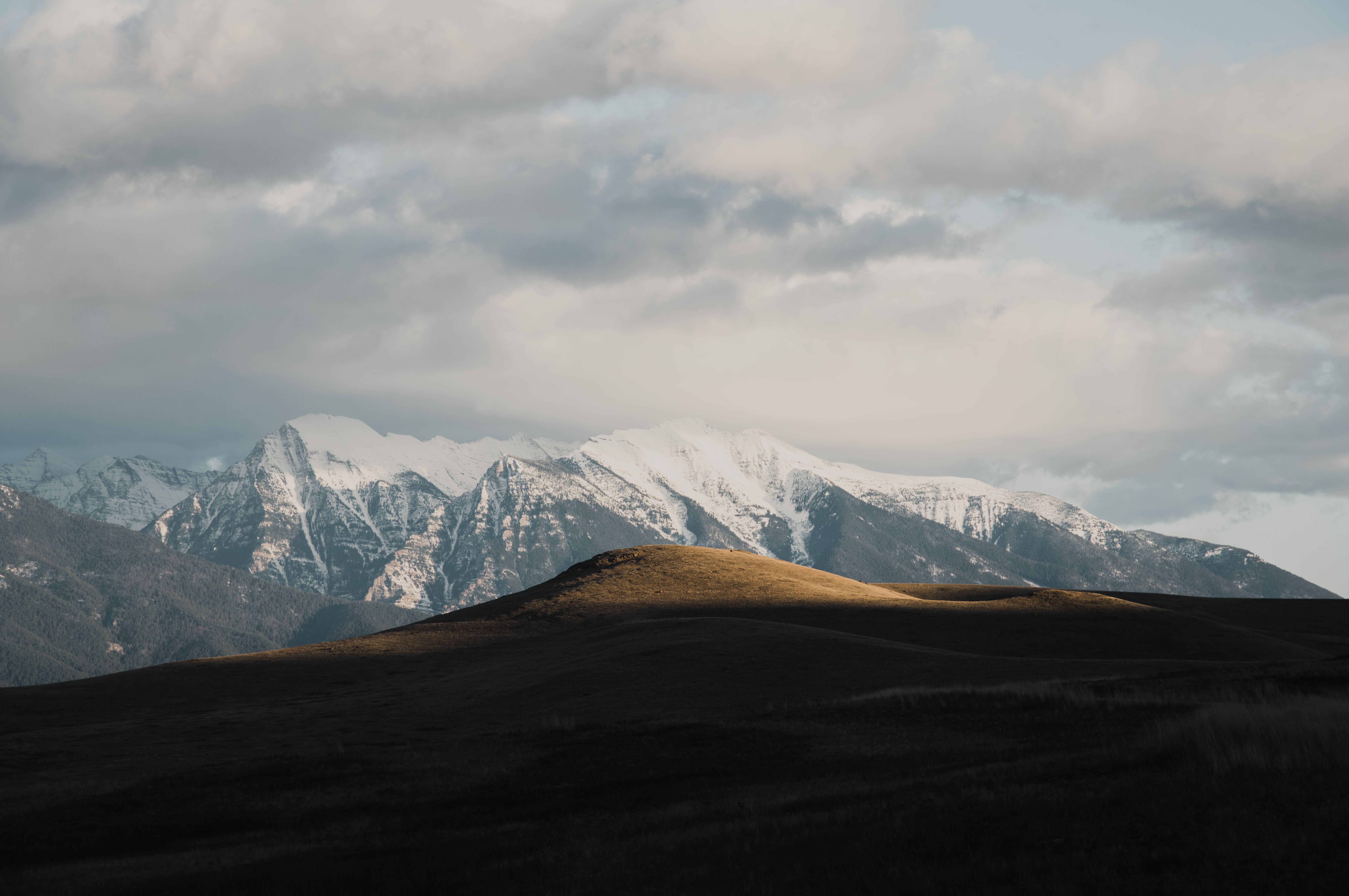 Golden foothills catching the last light below snow-capped Montana peaks