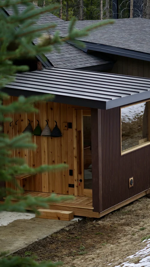 Cedar entry porch with felt sauna hats hanging on hooks beside the door