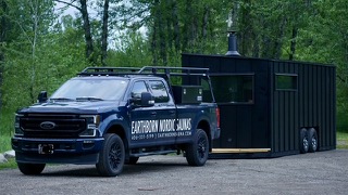 Truck towing the Earthborn mobile sauna trailer down a gravel road