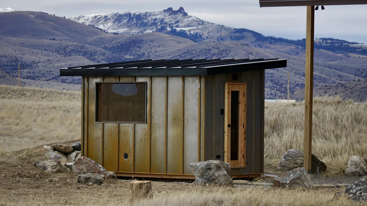 Rusted-panel Earthborn sauna set against the Montana mountains